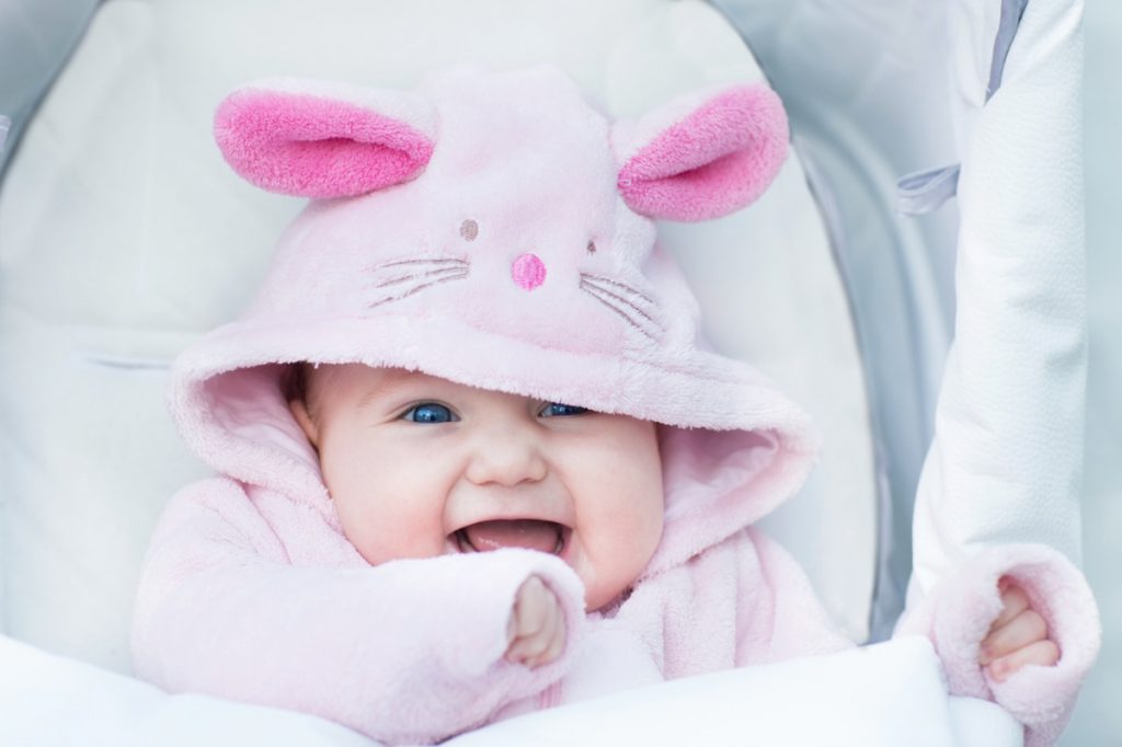 Adorable funny baby girl sitting in a stroller in a bunny snow s